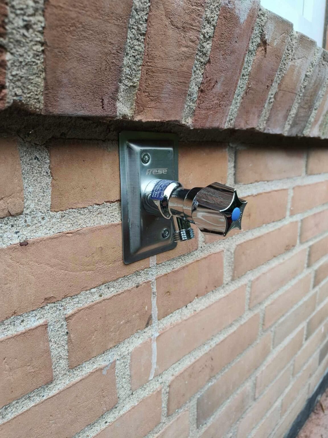 Vandhane monteret på murstensvæg udendørs