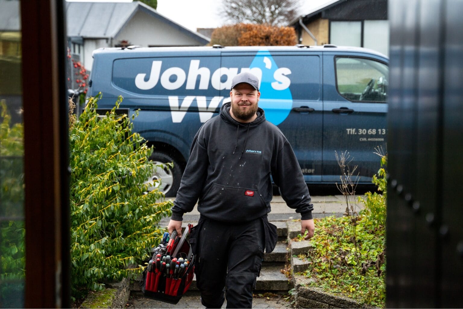 VVS-tekniker foran servicebil med værktøj.