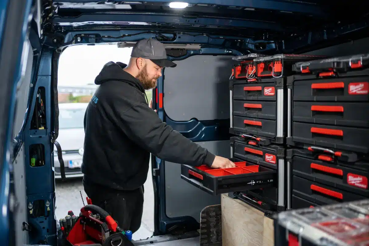 Mand organiserer værktøj i varevognens opbevaringsskab.
